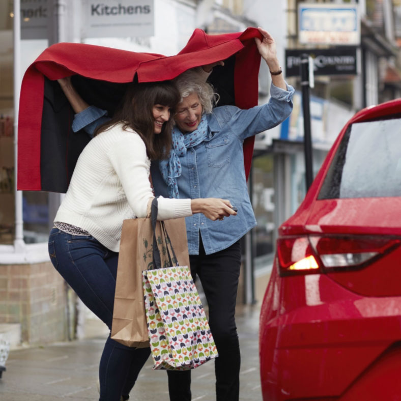 Two women shelter under car